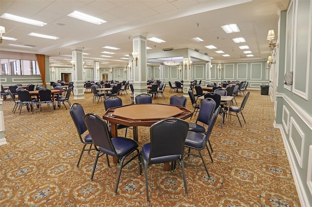 carpeted dining room with a paneled ceiling, ornate columns, and crown molding