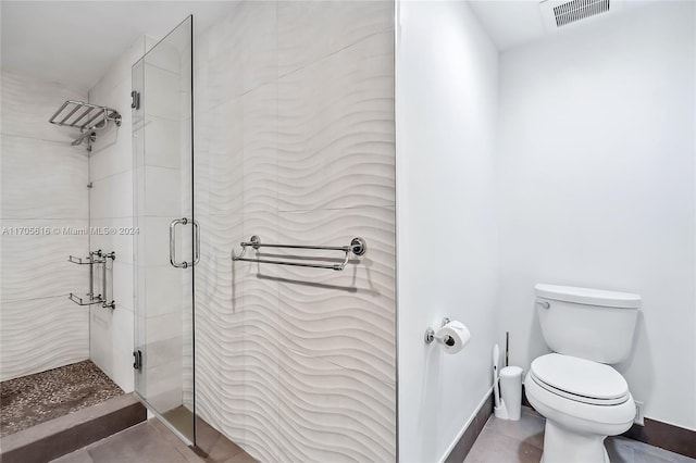 bathroom featuring tile patterned flooring, a shower with door, and toilet