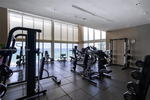 exercise room featuring expansive windows, a water view, and a wealth of natural light