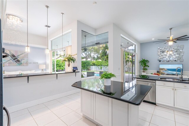 kitchen featuring white cabinets, appliances with stainless steel finishes, a kitchen bar, decorative backsplash, and hanging light fixtures