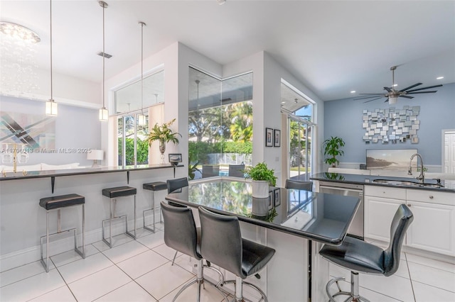 kitchen featuring decorative light fixtures, white cabinetry, sink, a breakfast bar, and stainless steel dishwasher