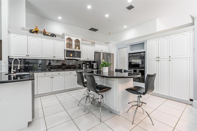 kitchen with a center island, appliances with stainless steel finishes, white cabinetry, sink, and a breakfast bar area