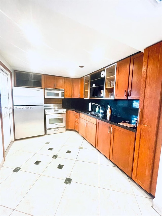 kitchen with light tile patterned floors, white appliances, tasteful backsplash, and sink