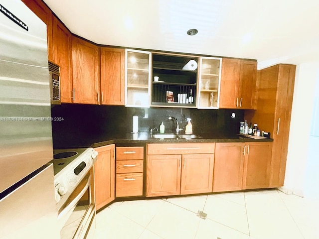 kitchen with stainless steel fridge, backsplash, sink, white range with electric cooktop, and light tile patterned flooring