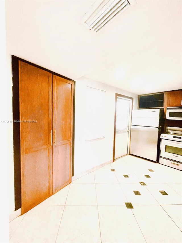 interior space with light tile patterned floors and white appliances