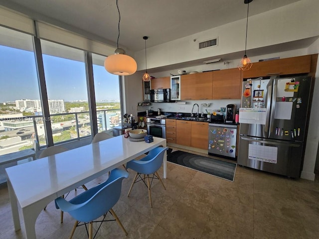 kitchen with decorative light fixtures, sink, and stainless steel appliances