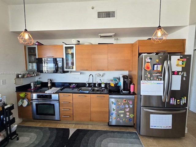 kitchen featuring sink, dark tile patterned floors, stainless steel appliances, and hanging light fixtures