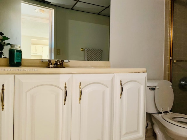 bathroom with vanity, toilet, and a drop ceiling