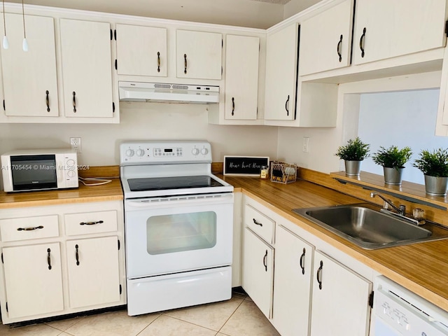 kitchen with light tile patterned floors, white appliances, white cabinetry, and sink