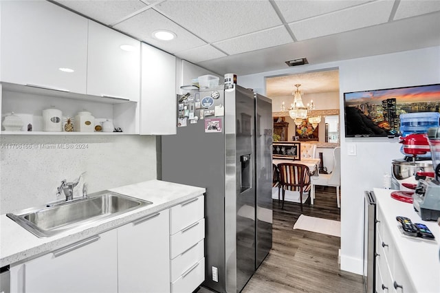 kitchen featuring stainless steel refrigerator with ice dispenser, sink, pendant lighting, light hardwood / wood-style floors, and white cabinetry