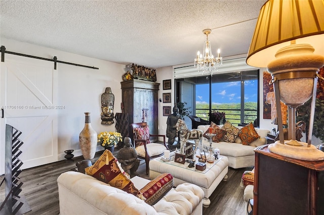 living room with a textured ceiling, a barn door, an inviting chandelier, and dark wood-type flooring