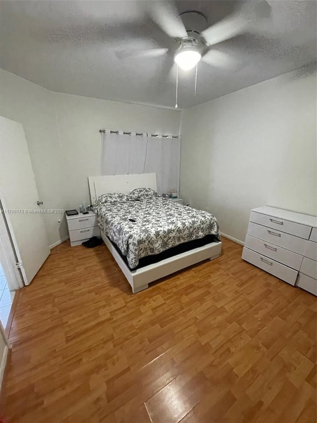 bedroom featuring a textured ceiling, light hardwood / wood-style floors, and ceiling fan