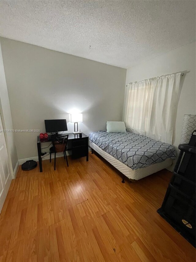 bedroom with hardwood / wood-style floors and a textured ceiling