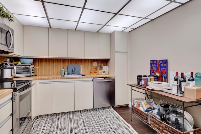 kitchen featuring a paneled ceiling, dark hardwood / wood-style flooring, white cabinetry, and appliances with stainless steel finishes