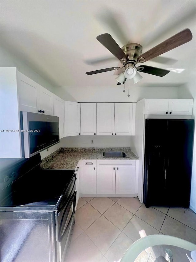 kitchen with light tile patterned flooring, white cabinetry, and black appliances