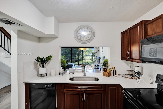 kitchen with black appliances, light hardwood / wood-style floors, sink, and a textured ceiling