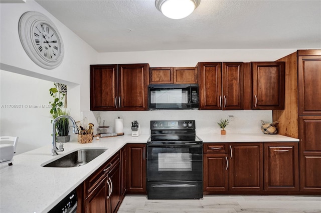 kitchen with sink, black appliances, a textured ceiling, and light hardwood / wood-style flooring