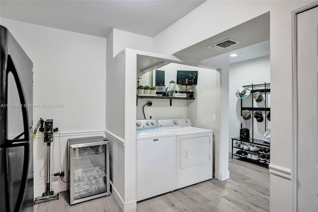 laundry area featuring light hardwood / wood-style flooring, washer and dryer, and a textured ceiling