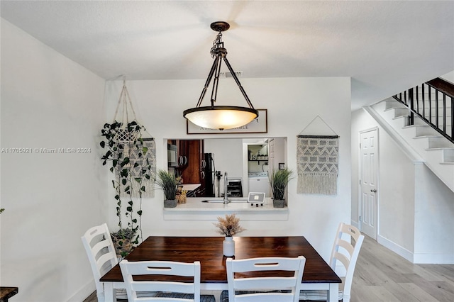 dining room with light hardwood / wood-style floors, sink, and washer / clothes dryer