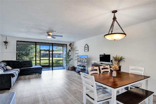 dining space featuring ceiling fan, a textured ceiling, and light wood-type flooring