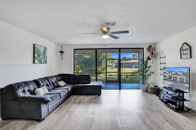 living room featuring ceiling fan, a textured ceiling, and light hardwood / wood-style flooring