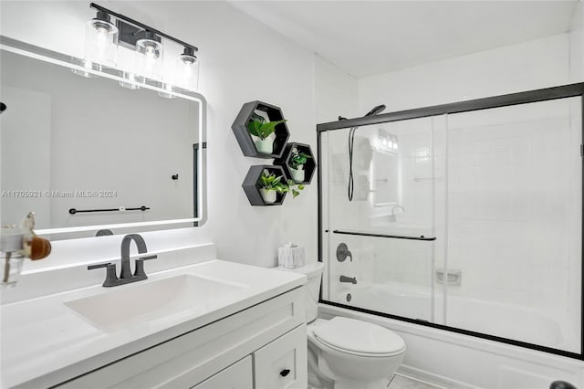 full bathroom featuring toilet, combined bath / shower with glass door, and vanity