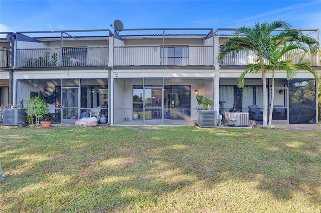 back of property with a lawn, a balcony, and central AC