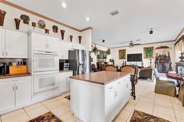 kitchen featuring white double oven, crown molding, ceiling fan, stainless steel fridge, and white cabinetry