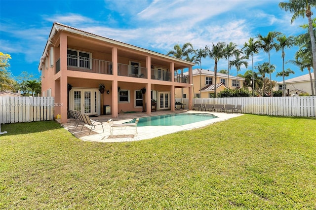 back of house featuring french doors, a balcony, a patio area, a fenced in pool, and a lawn