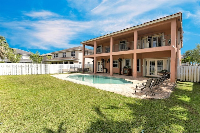 rear view of property with a lawn, french doors, a balcony, a fenced in pool, and a patio area