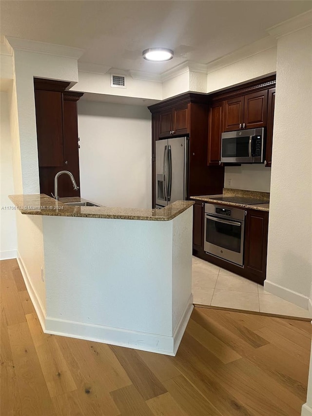 kitchen featuring light hardwood / wood-style floors, sink, kitchen peninsula, and stainless steel appliances