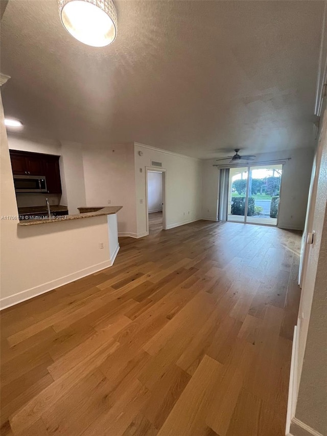 unfurnished living room with ceiling fan, hardwood / wood-style floors, and a textured ceiling