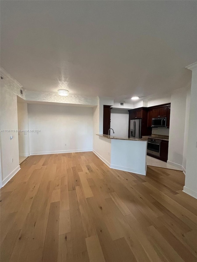 kitchen featuring kitchen peninsula, sink, light wood-type flooring, and appliances with stainless steel finishes