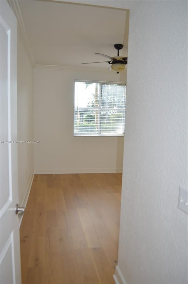 empty room with light wood-type flooring, ceiling fan, and ornamental molding