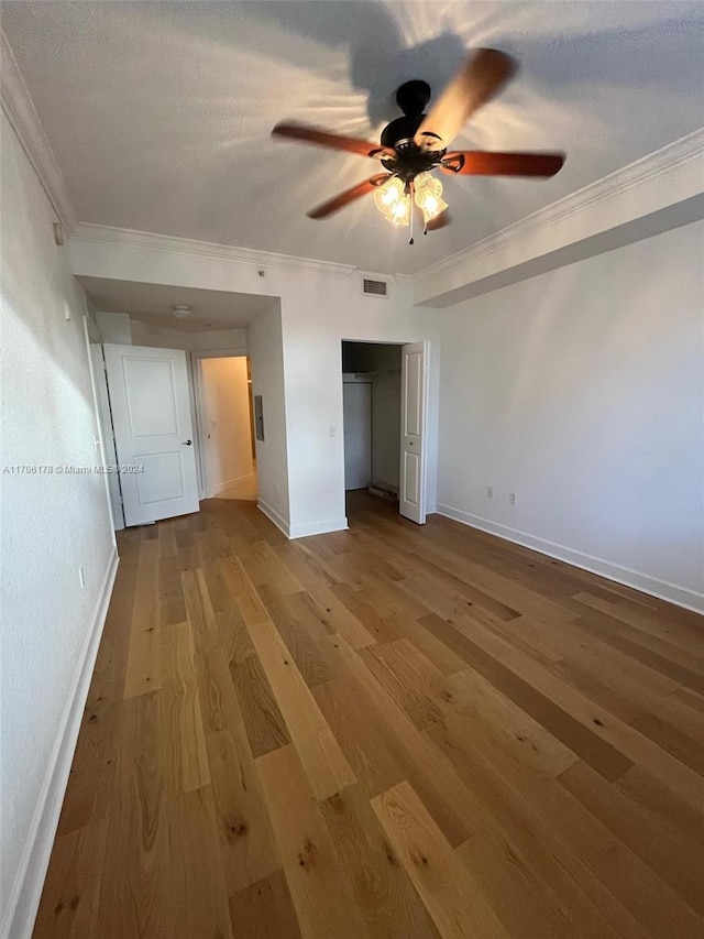 unfurnished bedroom featuring hardwood / wood-style flooring, ceiling fan, and crown molding