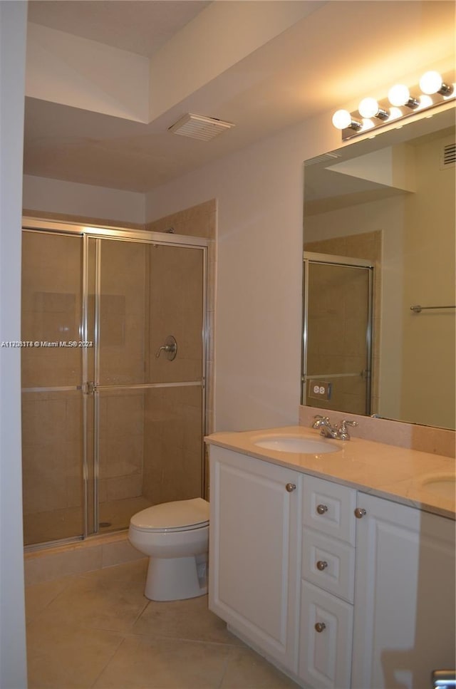 bathroom featuring toilet, vanity, tile patterned floors, and an enclosed shower