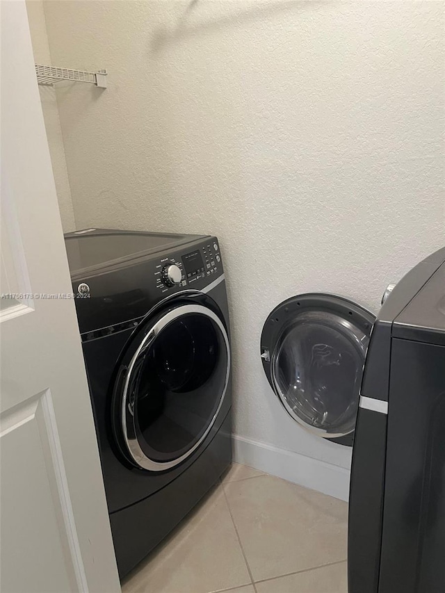 laundry area with light tile patterned floors and washing machine and clothes dryer