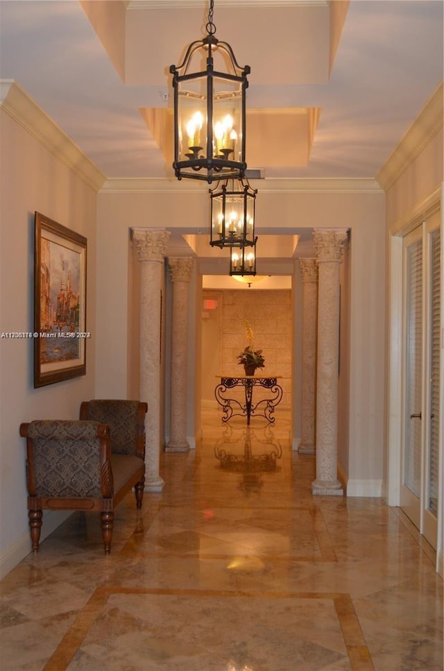 hallway featuring decorative columns, an inviting chandelier, and ornamental molding