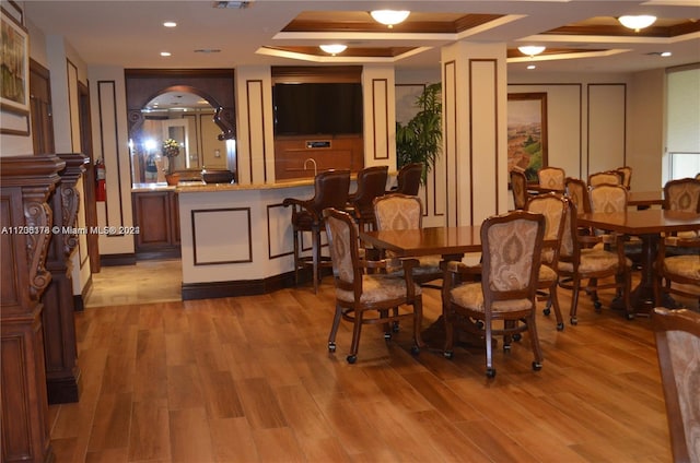 dining room featuring a raised ceiling and light hardwood / wood-style flooring