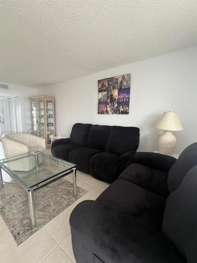 living area with light tile patterned floors, a textured ceiling, and visible vents
