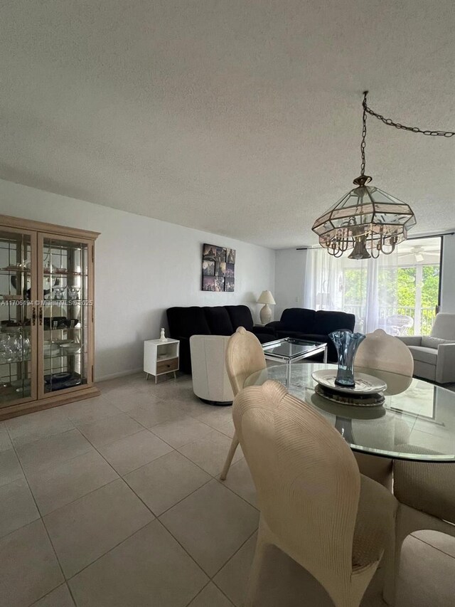 dining space featuring light tile patterned floors, a chandelier, and a textured ceiling