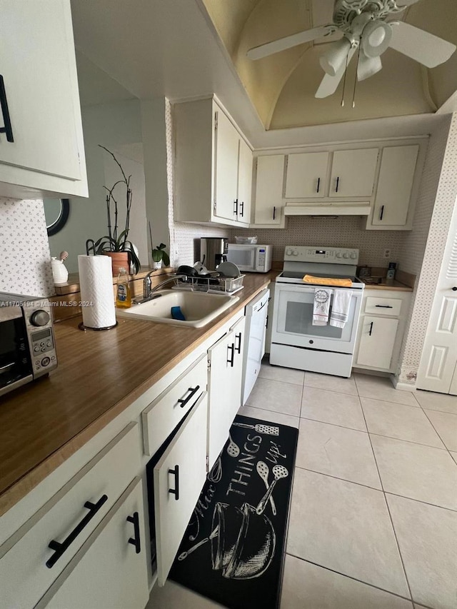 kitchen featuring white appliances, vaulted ceiling, sink, white cabinetry, and light tile patterned flooring