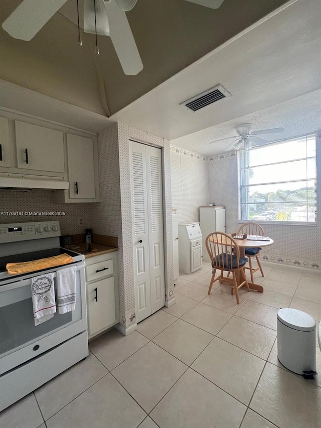kitchen featuring light tile patterned flooring, white range with electric stovetop, ceiling fan, under cabinet range hood, and visible vents