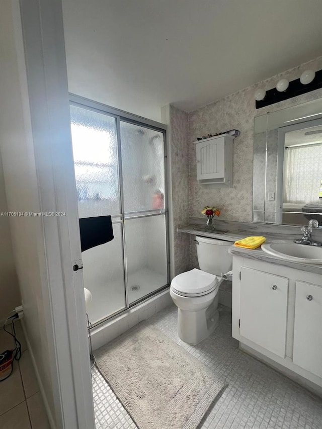 bathroom featuring toilet, vanity, tile patterned floors, and walk in shower