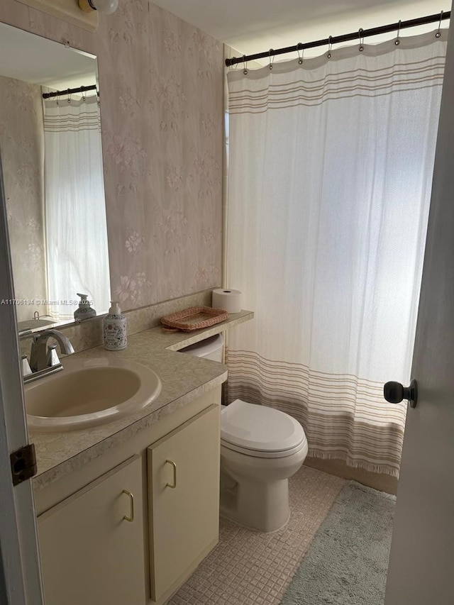 bathroom featuring vanity, tile patterned flooring, wallpapered walls, and toilet