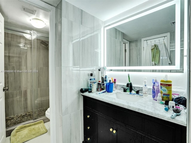 bathroom featuring vanity, a shower with shower door, and toilet