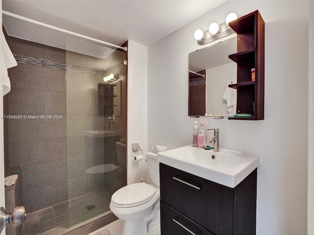 bathroom with a tile shower, vanity, and toilet