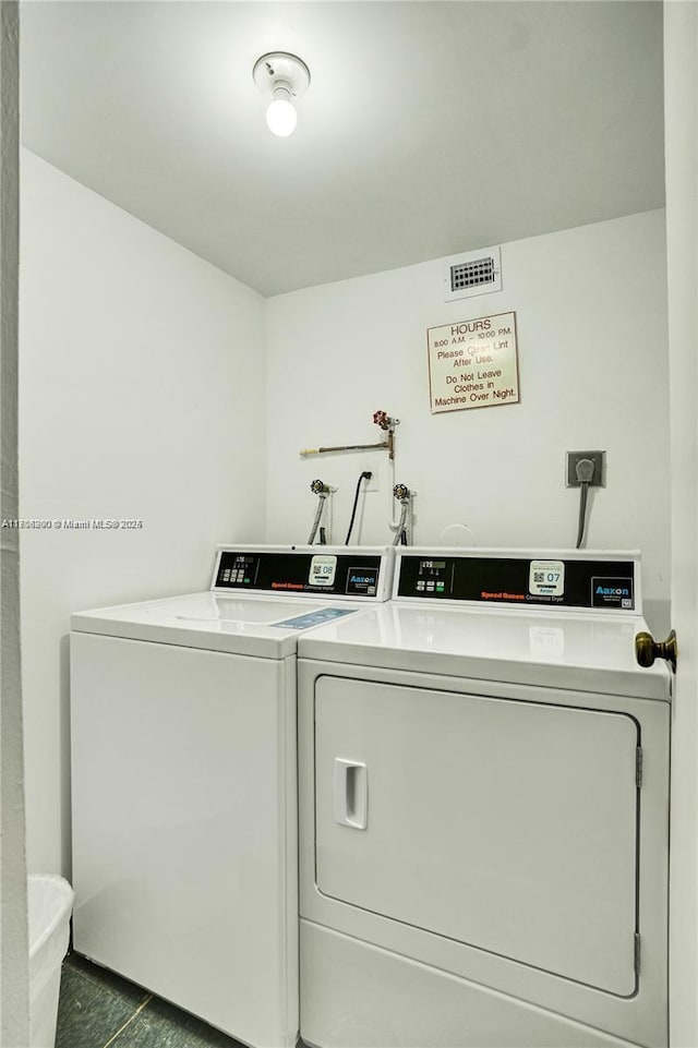 clothes washing area featuring dark tile patterned flooring and washing machine and dryer