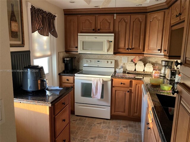 kitchen featuring backsplash, dark stone countertops, and white appliances