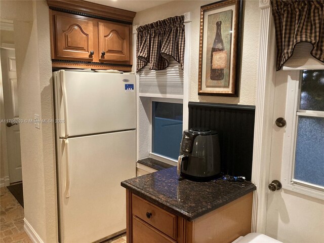 kitchen featuring white fridge and dark stone countertops